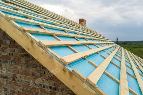 Preview: Aerial view of a brick house with wooden roof frame under construction