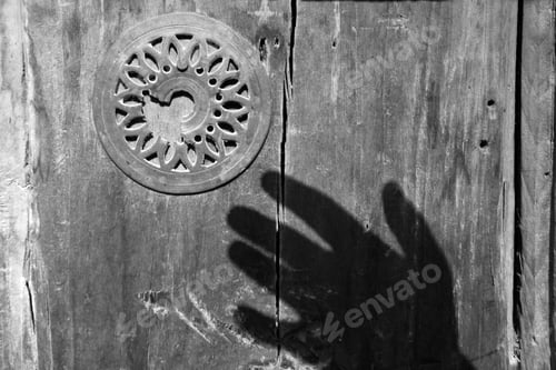 Preview: shadow of hand over old wooden door