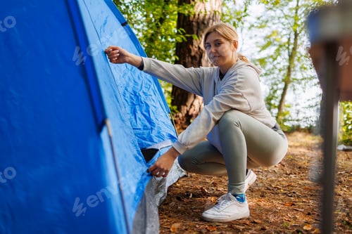 Preview: Woman opening a camping tent in a forest