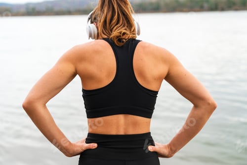 Preview: Female athlete resting after fitness training by riverside