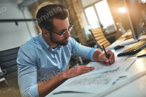 Preview: New project. Busy bearded engineer in eyeglasses and formal wear drawing something while working in