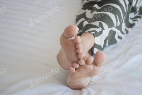 Preview: young Woman lying with bare feet in bed,