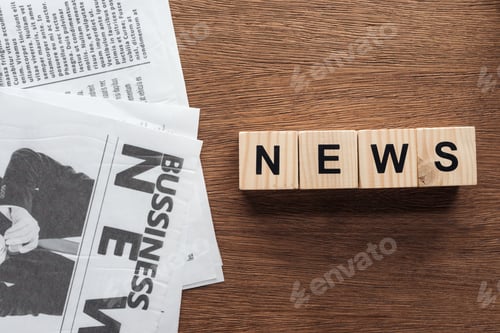 Preview: top view of wooden cubes with word news and business newspapers on wooden tabletop