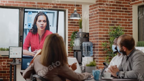 Preview: People with face mask talking on teleconference call to woman