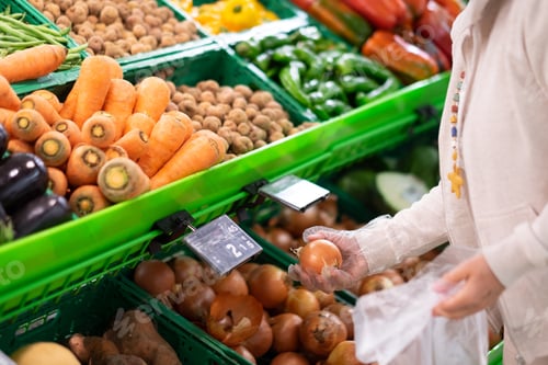 Preview: A senior woman choose onions at the supermarket. A counter full of various types of vegetable