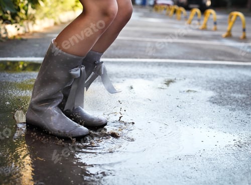 Preview: Woman wearing grey polka dots rain boots jumping into a puddle