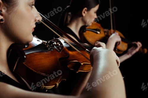 Preview: young professional musicians playing classical music on violins on dark stage