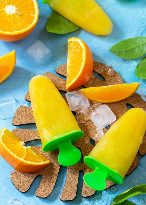 Preview: Homemade popsicles with orange juice, fruit ice on a blue stone or slate background.