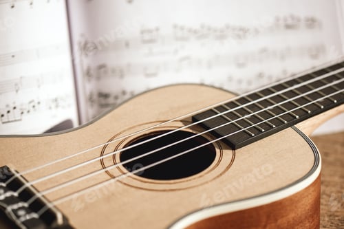 Preview: Ukulele chords. Close-up photo of ukulele guitar and music notes against of wooden background