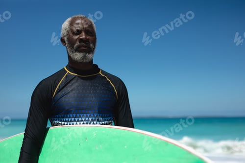 Preview: Old man with a surfboard at the beach