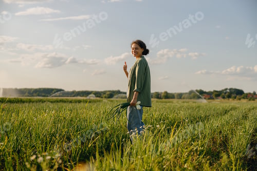 Preview: Smiling female farmer standing on field and showing thumb up. Agriculture concept
