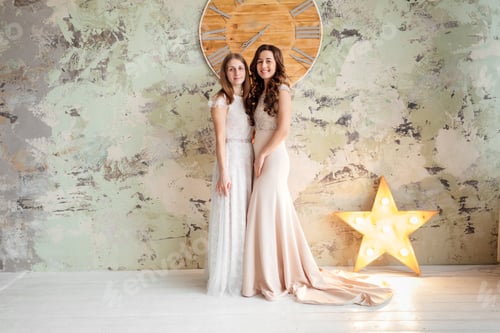 Preview: two gorgeous young women dressed in exquisite nude long dresses with lace top. Attractive female