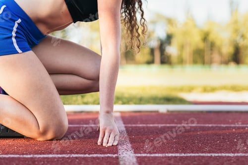 Preview: Focused female athlete prepared to run on an athletics track
