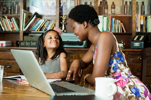 Preview: Mother and daughter using laptop at home