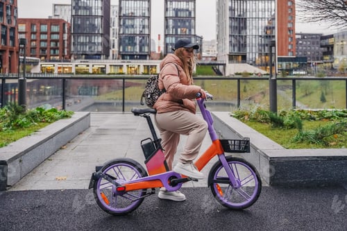 Preview: Riding rented electric bicycle during rainy commute. Ebike rental sharing supports urban transport
