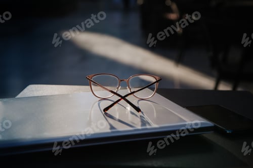 Preview: Glasses and Phone on Laptop Computer in Sunlight
