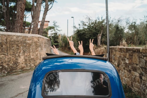 Preview: Friends gesturing peace sign in car sunroof, Florence, Toscana, Italy