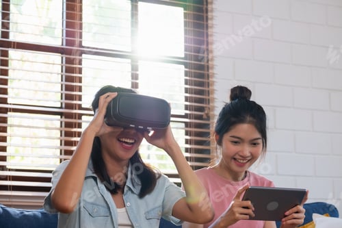 Preview: Happy asian lesbian play virtual reality goggle with tablet