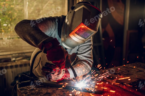 Preview: Man worker welding metal with welding machine in a factory or workshop