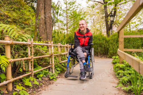 Preview: Portrait of a paralyzed young man in a public park in the city. Sitting in the wheelchair strolling