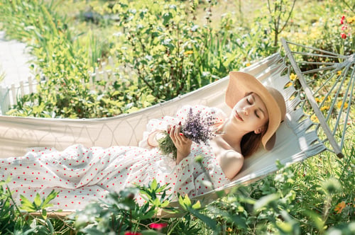 Preview: Young woman relaxing in a hammock outdoors in back yard