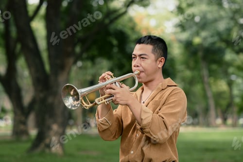 Preview: Musician performs with trumpet in a green public park