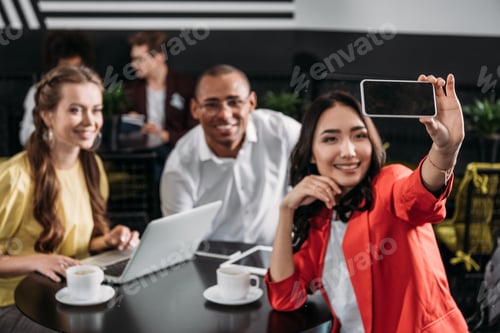 Preview: group of young business partners taking selfie in cafe