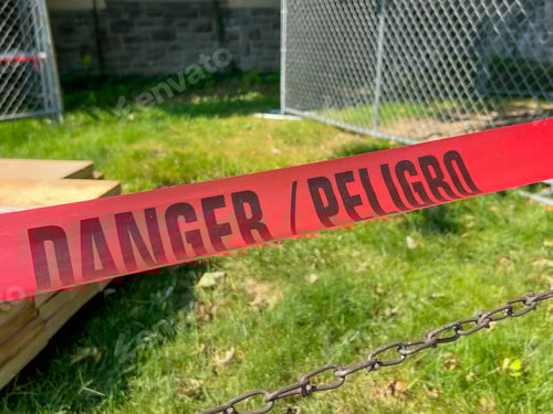 Preview: Danger in English and Spanish Red Tape with Black Lettering Warning a Restricted Access to an Area