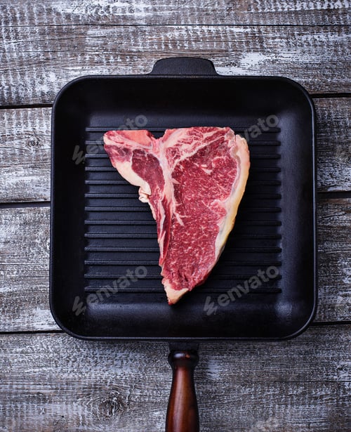 Preview: Raw T-bone steak on iron grill pan