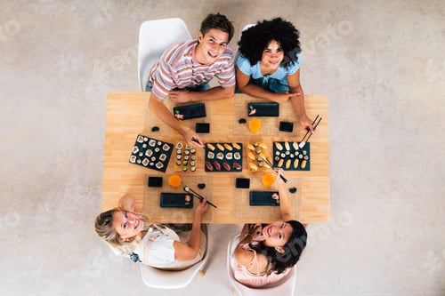 Preview: Multiethnic group of young friends meeting at home and eating sushi