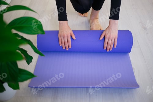 Preview: Woman Rolling Out Yoga Mat in Bright Room