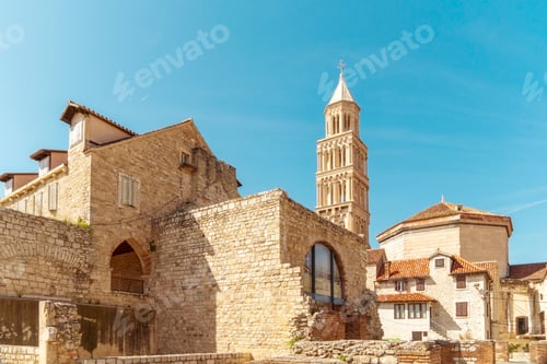 Preview: Sunlit view of an old stone church with a bell tower of St Domnius, situated in a