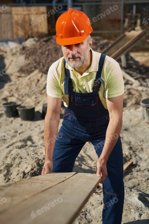 Preview: Worker putting plank end on ground at building area