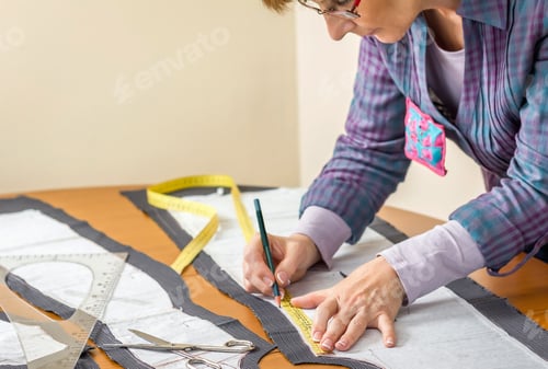 Preview: Dressmaker drawing tailor pattern on the table