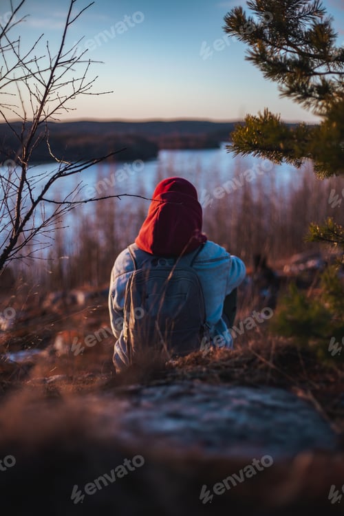 Preview: lonely man sitting and looking at sunset behind a river dramatic and loneliness,