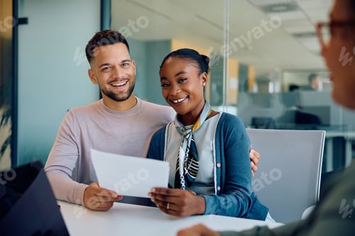 Preview: Young happy couple during a meeting with bank manager looking at camera.