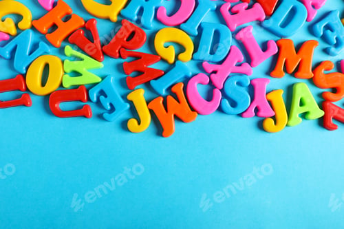 Vorschau: Viele bunte Magnetbuchstaben auf hellblauem Hintergrund, flach gelegt. Platz für Text
