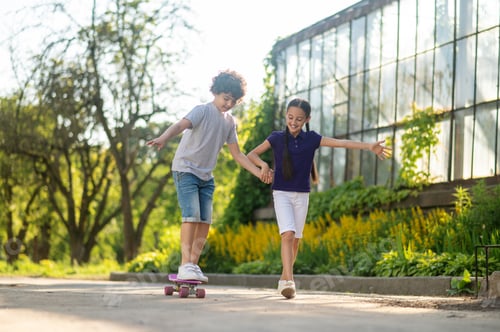 Preview: Boy learning to ride the skateboard aided by a girl