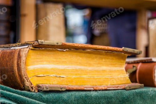 Preview: Second hand books for sale on a market stall. Old faded yellowing hardback. Blurred background.