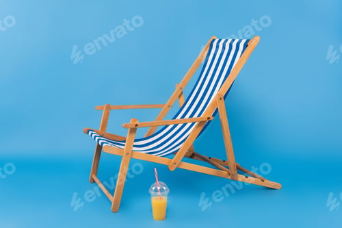 Preview: Orange juice near deck chair on blue background