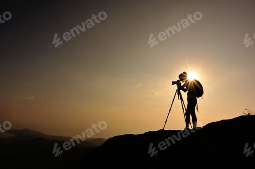 Preview: woman photographer taking photo on sunset mountain peak