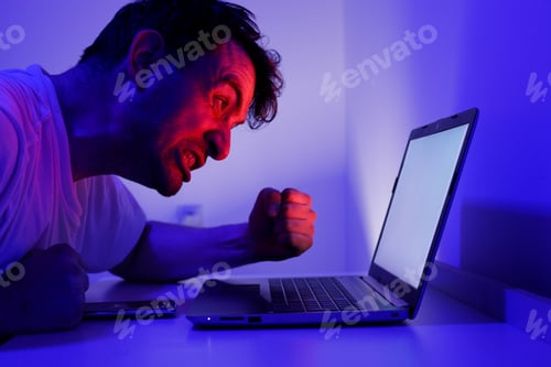 Preview: Man reacts strongly while using laptop during late-night work session at home