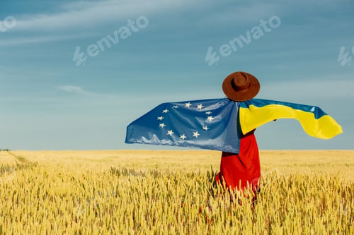 Preview: Girl with Ukraine and EU flags in wheat field and blue sky on background