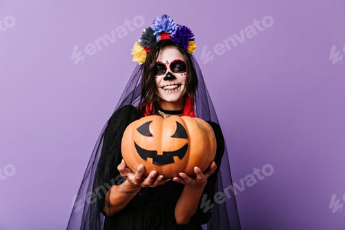 Preview: Smiling zombie girl in black veil posing on pastel background. Glad woman in dead bride outfit hold