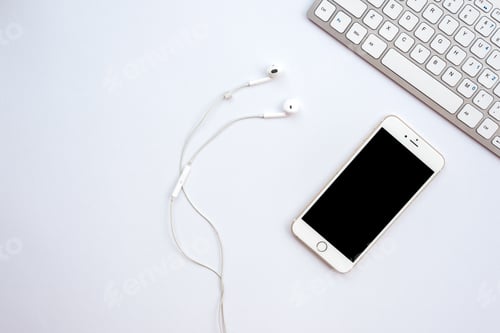 Preview: White office desk with a smartphone, earphones - Top view