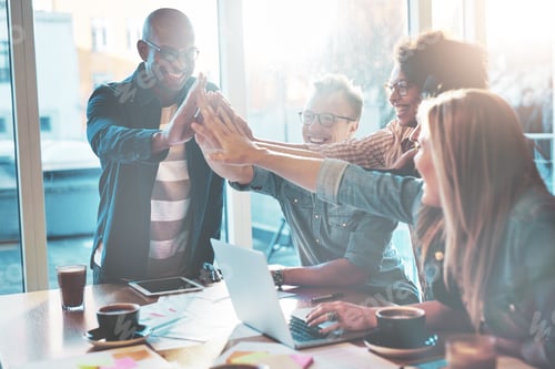 Preview: High fiving coworkers at table in office