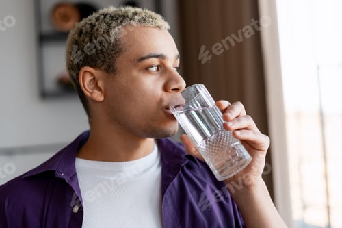 Preview: Young man drinking water, hydrating for health and refreshment indoors