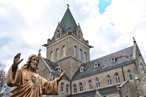 Preview: Stone church European Architecture with Sacred Heart of Jesus welcoming statue in front Faith