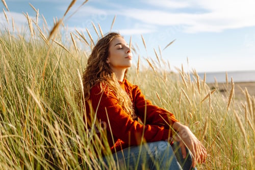 Preview: Beautiful young woman enjoying nature outdoors in tall grass. Flying hairs. Lifestyle. Fashion style