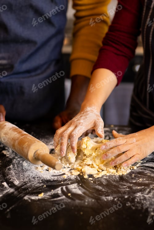 Preview: Midsection of diverse couple baking, preparing dough in kitchen, copy space